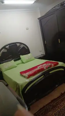 a bedroom with a bed with green sheets and a dresser at الاقصر امتداد ش التليفزيون in Al Bayāḑīyah
