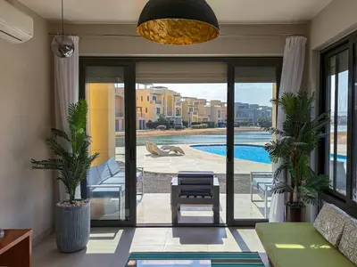 a living room with a view of a swimming pool at Vibrant 3BR Villa - Free Pool & Lagoon Access At ElGouna in Hurghada