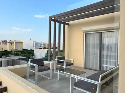 a balcony with two chairs and a glass table at Vibrant 3BR Villa - Free Pool & Lagoon Access At ElGouna in Hurghada