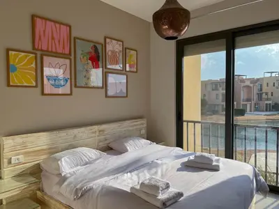 a bedroom with a large bed and a balcony at Vibrant 3BR Villa - Free Pool & Lagoon Access At ElGouna in Hurghada