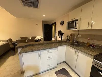 a kitchen with white cabinets and a living room at Sun & Fun Aldau Heights one bedroom apartment in hurghada in Hurghada
