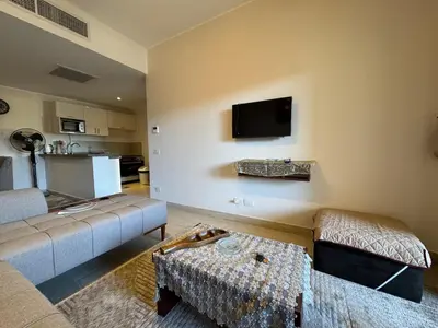 a living room with a couch and a tv on the wall at Sun & Fun Aldau Heights one bedroom apartment in hurghada in Hurghada