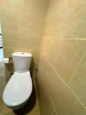 a bathroom with a white toilet in a tiled wall at Aldau Heights one bedroom apartment in Hurghada cr in Hurghada