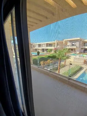 a window with a view of a building and a palm tree at Gcribs B7F7 in El Gouna
