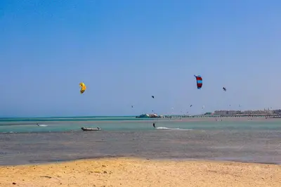 a group of people flying kites on the beach at Selena Bay Resort in Hurghada
