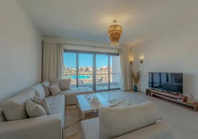 a living room with white furniture and a large window at Brand-New 1BR in Kamaran El Gouna I Pool View & Access in Hurghada