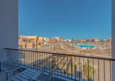 a balcony with chairs and a view of a playground at Brand-New 1BR in Kamaran El Gouna I Pool View & Access in Hurghada