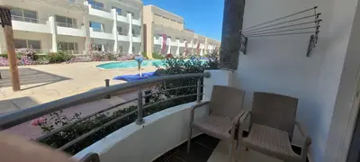 a balcony with two chairs and a swimming pool at Apartment With Free Private Beach Furnished Near senzomall in Hurghada