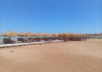 a beach with umbrellas and chairs on the beach at Fanadir Bay - beach & Aquapark in Hurghada
