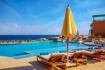 a pool with chairs and a yellow umbrella at Seaview Apartment in Azzurra Sahl Hasheesh 2 bedrooms in Hurghada