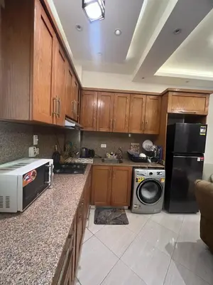 a kitchen with wooden cabinets and a black refrigerator at Sunflower cozy apartment in Hurghada