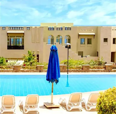 a blue umbrella and chairs next to a swimming pool at Apartment Azzura Sahl Hasheesh with Private Garden and Sea view in Hurghada