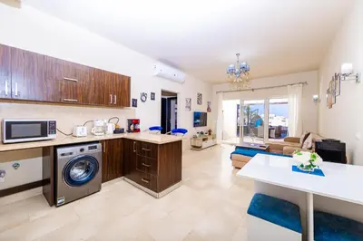 a kitchen and living room with a washer and dryer at Apartment Azzura Sahl Hasheesh with Private Garden and Sea view in Hurghada