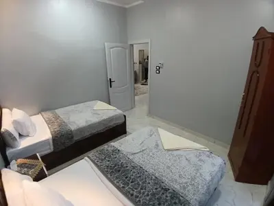 a room with two beds and a door to a bathroom at Hakuna Matata in Aswan