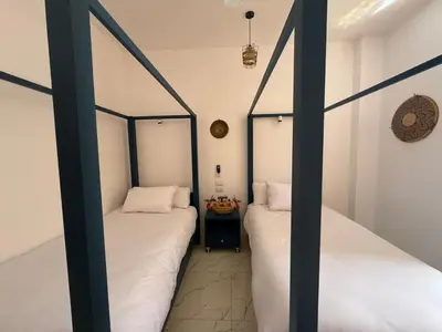 two twin beds in a room with white walls at El Bawaba Lodge & Luxury Retreat in Al Aqālitah