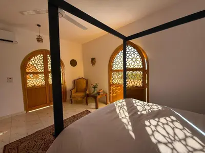 a bedroom with a bed and a chair at El Bawaba Lodge & Luxury Retreat in Al Aqālitah