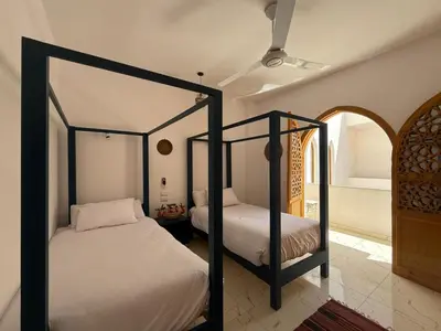 two twin beds in a room with a bedroom at El Bawaba Lodge & Luxury Retreat in Al Aqālitah