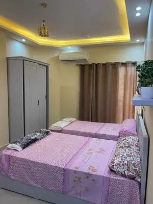 a bedroom with two beds with pink sheets and a curtain at Studio in Hurghada