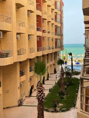 a large building with palm trees in front of the beach at Studio in Hurghada