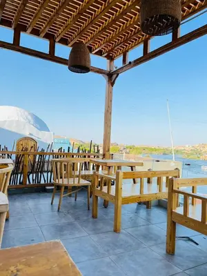 a patio with wooden tables and chairs and a view of the water at nubiary in Jazīrat Salūjah