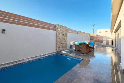 a swimming pool with chairs and a table next to a building at Bali 2 BR private pool el gouna heated pool in Hurghada