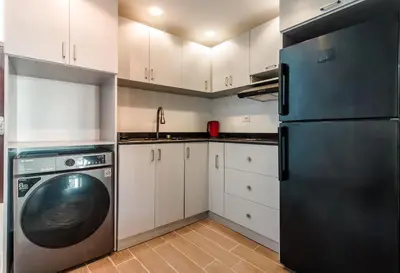 a kitchen with white cabinets and a black refrigerator at Al Saraya Sahl Hasheesh by Peaks Studio with Pool View C106 in Hurghada