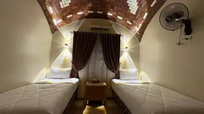 two beds in a room with an arched ceiling at Lilys Garden Guest House in Jazīrat al ‘Awwāmīyah
