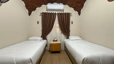 two beds in a room with a window at Lilys Garden Guest House in Jazīrat al ‘Awwāmīyah
