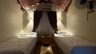 two twin beds in a room with a window at Lilys Garden Guest House in Jazīrat al ‘Awwāmīyah