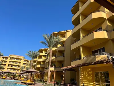 a resort building with a palm tree and a swimming pool at ATO luxurious apartments in Hurghada