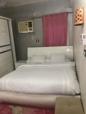 a bedroom with a large white bed with a pink curtain at HAWATY NUBA DWeLL in Nag` el-Ramla
