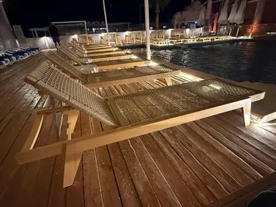 a row of benches sitting on a deck next to the water at Luxury Selena Bay Apartment- Private Beach, Kite School 5 Pools in Hurghada