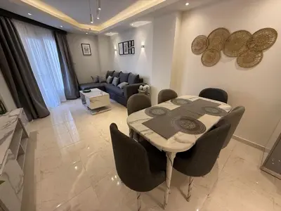 a living room with a table and chairs and a couch at Luxury Selena Bay Apartment- Private Beach, Kite School 5 Pools in Hurghada
