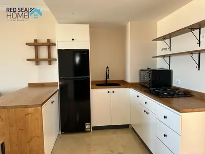 a kitchen with a black refrigerator and white cabinets at Luxury Apartment In The View in Hurghada
