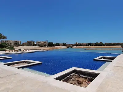 a swimming pool with blue water in a resort at El Gouna 1 Bedroom Waterside in Hurghada