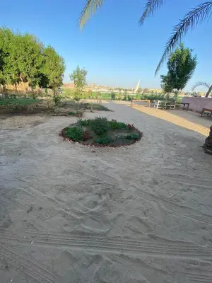 a park with a flower bed in the sand at Nile Garden Apartments in Luxor