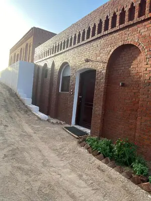 a brick building with a door on a dirt road at Nile Garden Apartments in Luxor