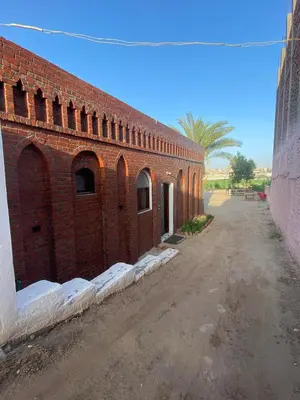 a red brick building with a dirt road next to it at Nile Garden Apartments in Luxor