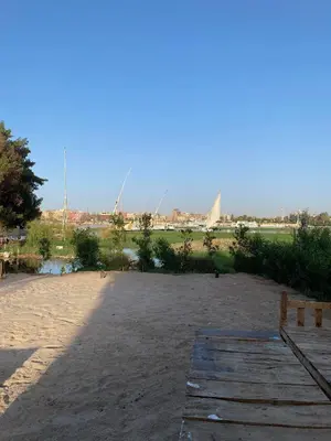 a sandy field with a bridge and a river at Nile Garden Apartments in Luxor