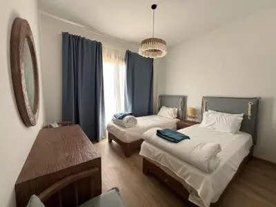 a bedroom with two beds and a table and a mirror at Kamaran 2BR • Luxurious Retreat in Hurghada