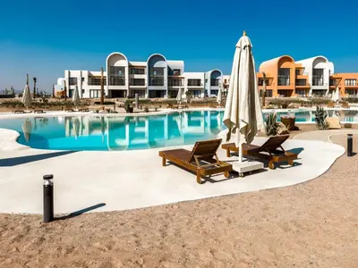 a swimming pool with two chairs and an umbrella at Kamaran 2BR • Luxurious Retreat in Hurghada