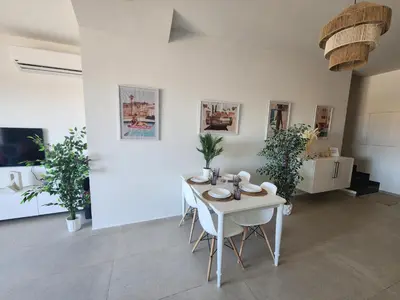 a room with a white table and chairs and plants at Duplex 1BR King Bed and1 Sofa Bed By the Pool in Hurghada