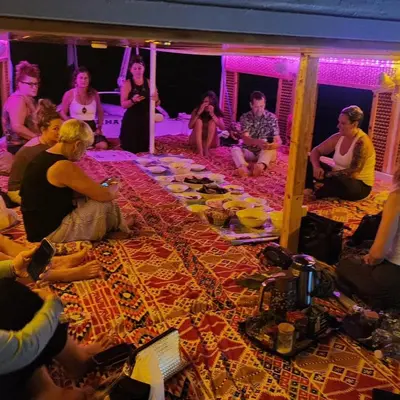 a group of people sitting around a table with food at Rayan Nubian Guest House in Aswan