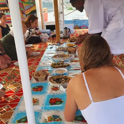 a group of people sitting around a table with food at Rayan Nubian Guest House in Aswan