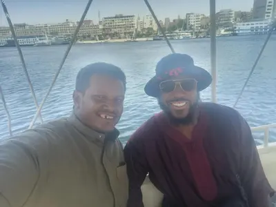 two men standing on a boat in the water at Rayan Nubian Guest House in Aswan