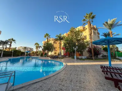 a swimming pool in front of a building with palm trees at Apartment with a private roof top , pool , Garden in Hurghada