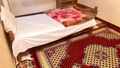 a bed with a white blanket and a rug on a floor at Family Flat With Breakfast in Luxor