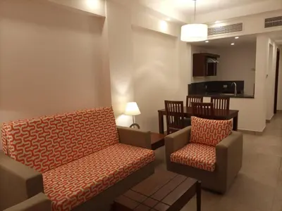 a living room with a couch and chairs and a kitchen at Oyster bay resort studio in Marsa Alam