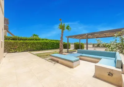 a blue couch on a patio with a palm tree at Prime 4BR Villa in Ancient Sands, El Gouna Private Swimming Pool & Lagoon Access in Hurghada