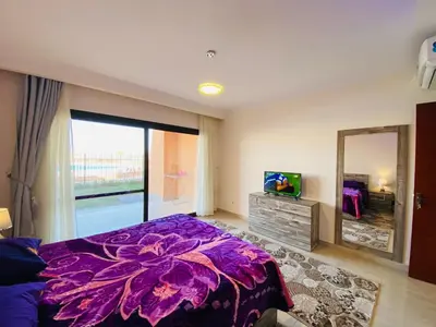 a bedroom with a purple bed and a mirror at The Clubhouse Apartment in Hurghada
